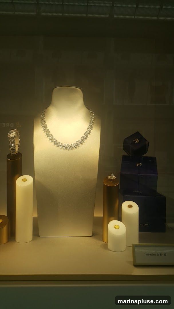 A display case showcases a diamond necklace on a mannequin bust, a diamond bracelet on a stand, and rings on stands. Several dark blue boxes, some with gold accents, are stacked to the right. A small plaque reads "Joséphine" with Chinese characters.
