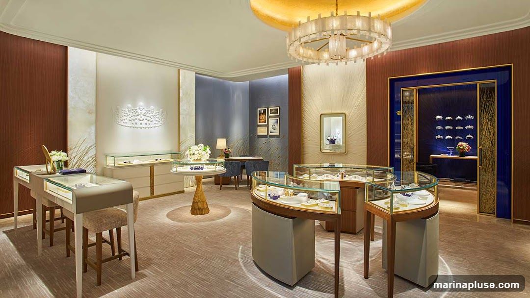 The interior of a high-end jewelry store, featuring elegant display cases filled with jewelry, a large decorative crown on the wall, and a modern chandelier. The store has a sophisticated ambiance with warm lighting and plush carpeting.