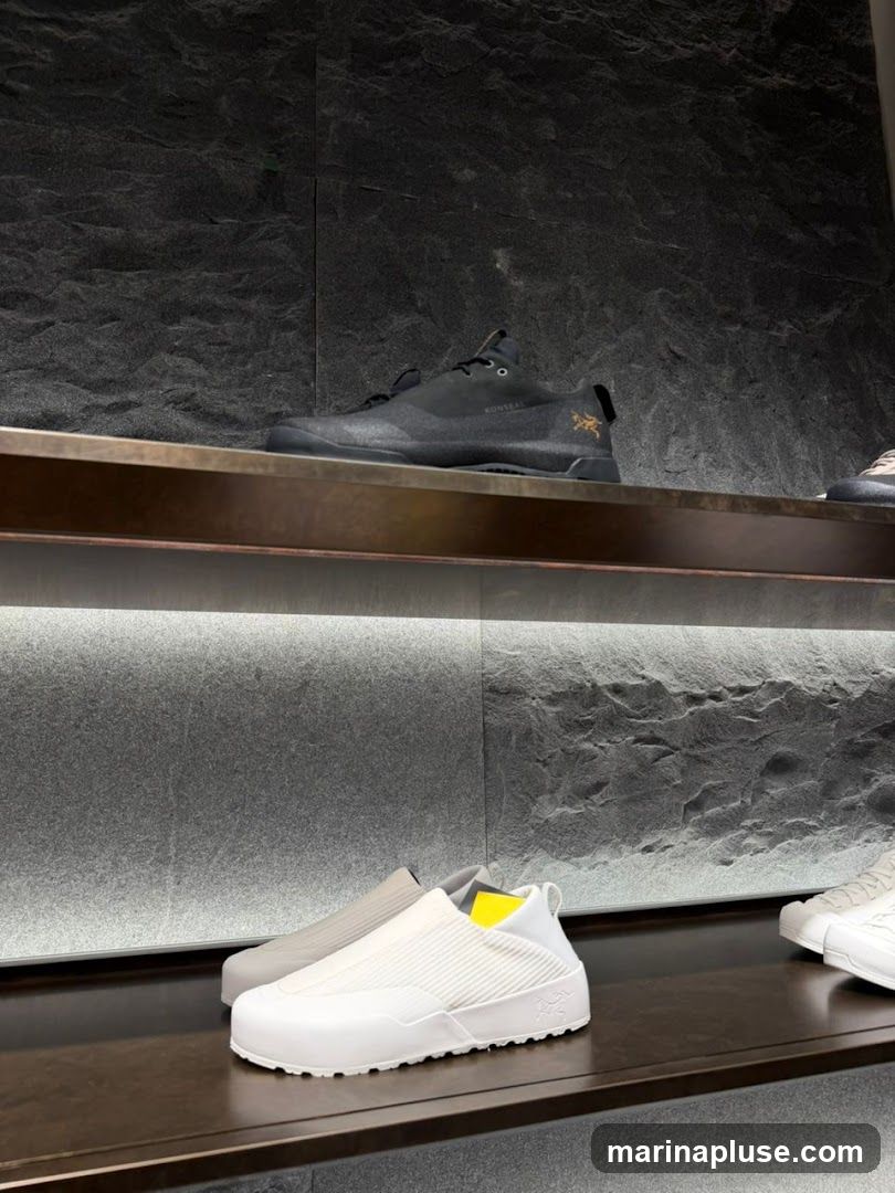 A close-up shot of shoes displayed on shelves in a store. The shoes are modern and stylish, with a focus on comfort and performance. The shelves are made of dark wood and are lit by soft, ambient lighting. The background is a textured stone wall.