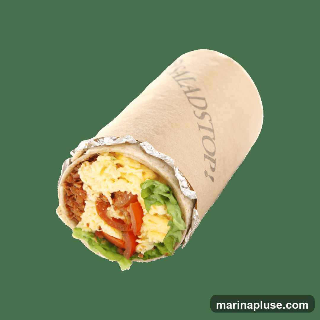 A close-up studio shot of a Saladstop! wrap against a black background. The wrap is made with a brown paper wrapper, with the Saladstop! logo visible on the wrapper. The filling of the wrap is visible at the bottom, showing scrambled eggs, shredded meat, lettuce, and tomato slices.