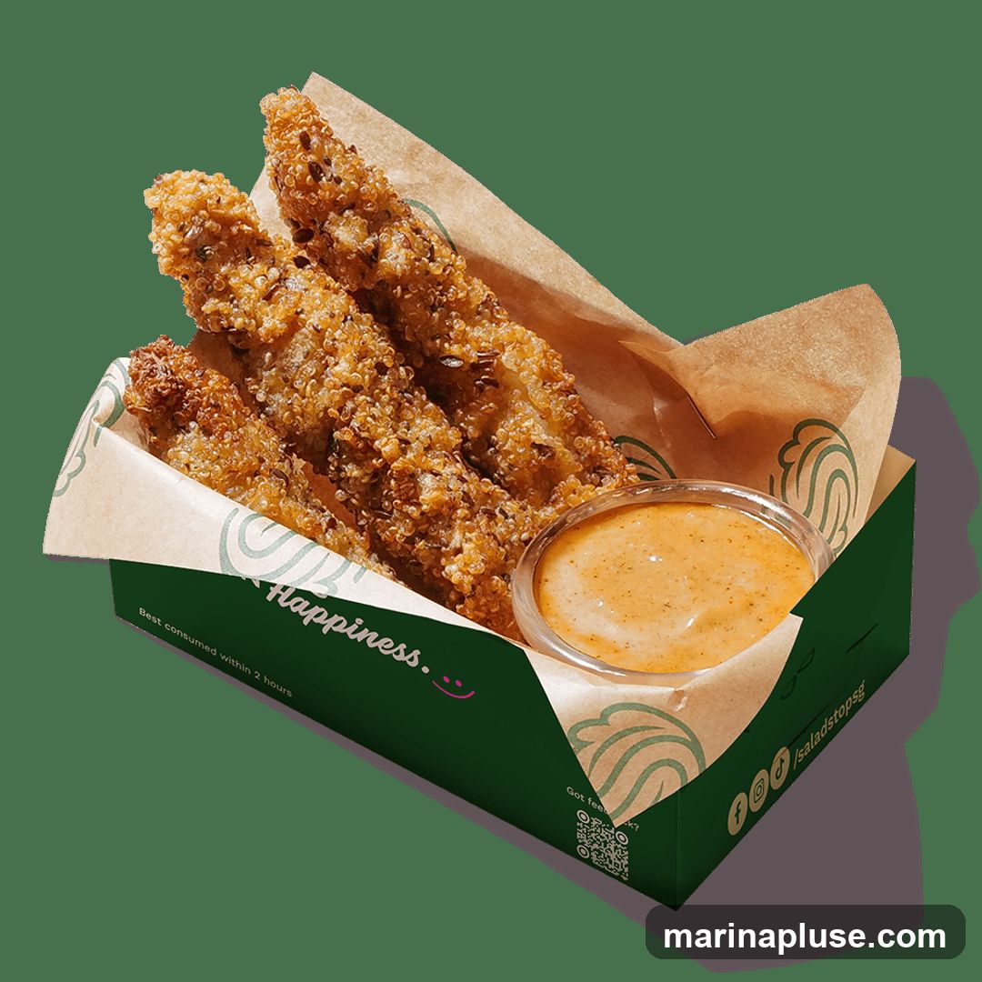 Three crispy, golden-brown strips coated in quinoa and seeds, served in a green cardboard container with a small cup of creamy orange dipping sauce. The container has green branding with a wave-like logo and text that reads "Happiness." and "Best consumed within 2 hours".