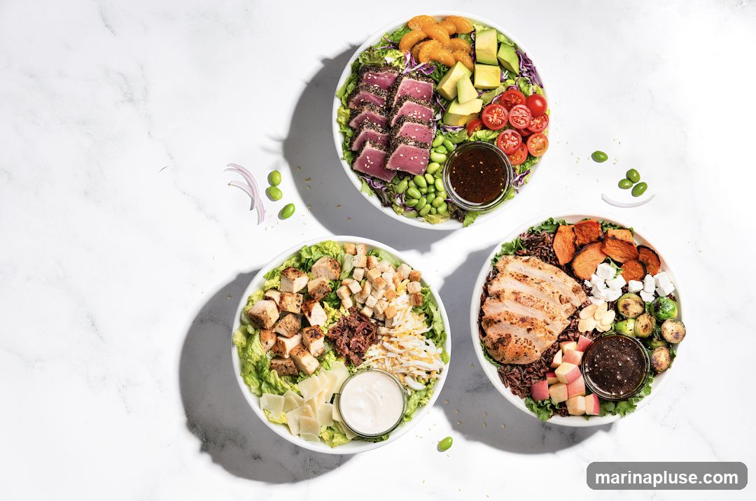 Three overhead shots of vibrant salad bowls arranged on a white marble surface. The bowls contain a variety of fresh ingredients, including seared tuna, grilled chicken, avocado, edamame, cherry tomatoes, sweet potatoes, Brussels sprouts, and various greens. Each bowl is accompanied by a small dish of dressing.