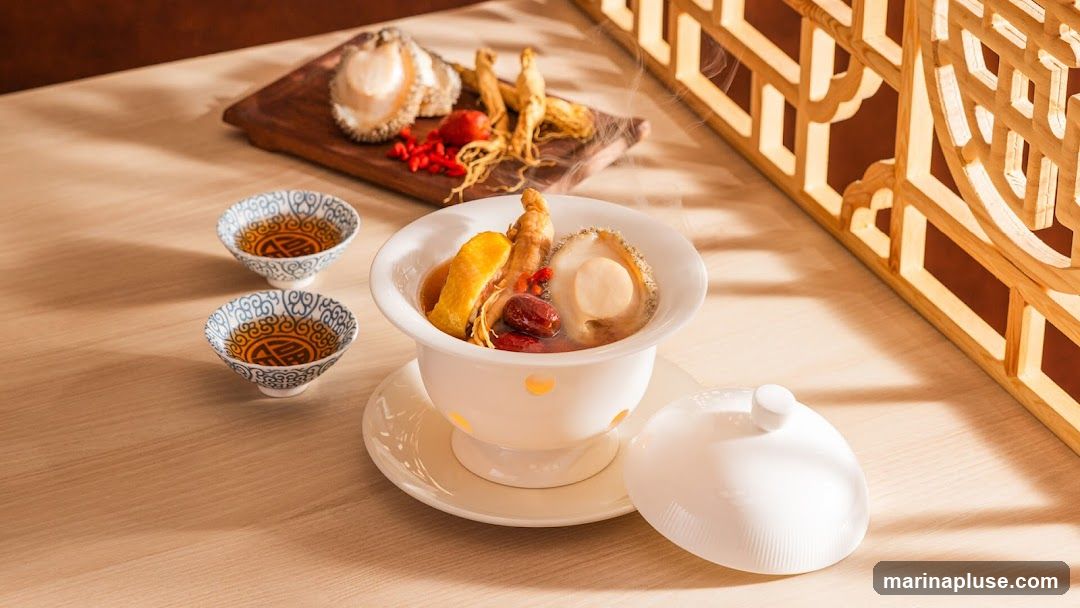 A steaming bowl of abalone and ginseng soup is presented on a wooden table, accompanied by two small cups of tea. The soup contains a whole abalone, pieces of chicken, ginseng roots, and red dates. In the background, a wooden lattice screen casts shadows on the table.