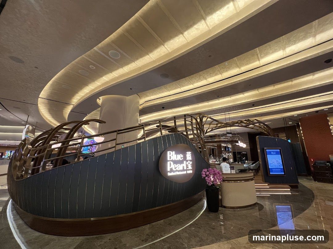 A view of the interior of a restaurant with a distinctive boat-like seating area. The restaurant's name, "Blue Pearl Seafood Restaurant," is visible on a circular sign. The interior features modern lighting and a bar area.