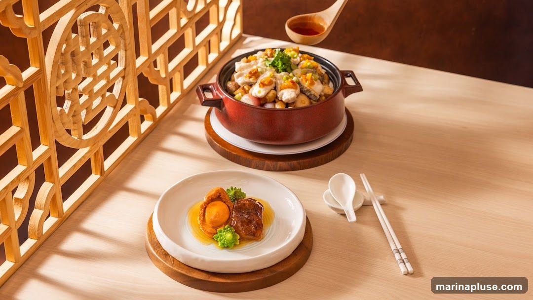 A close-up shot of a beautifully presented meal. In the foreground, a white plate holds a piece of abalone and braised pork belly, garnished with broccoli florets and bathed in a savory sauce. Behind it, a rustic red pot contains a hearty stew with visible chunks of fish, vegetables, and toppings, being drizzled with a sauce from a wooden spoon. The scene is set against a backdrop of traditional wooden lattice work and a warm, wooden table, creating an elegant and inviting atmosphere.