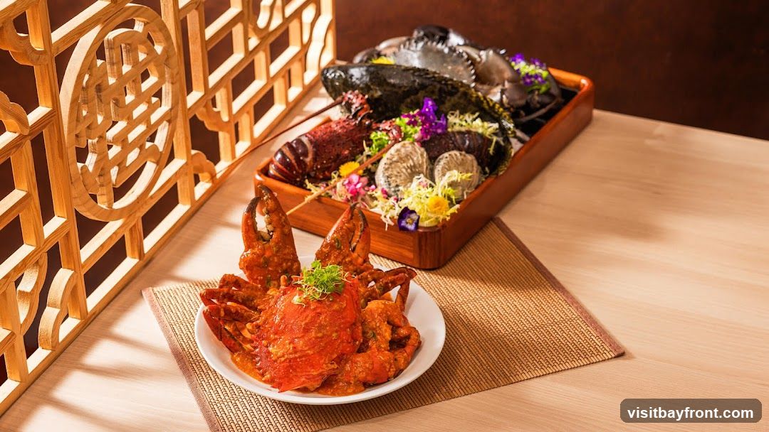 A close-up shot of a seafood platter featuring a whole crab in a rich orange sauce in the foreground, and a larger platter with lobster, crabs, and oysters in the background. The dishes are garnished with fresh herbs and edible flowers, set against a backdrop of a wooden lattice screen and a light-colored wooden table.