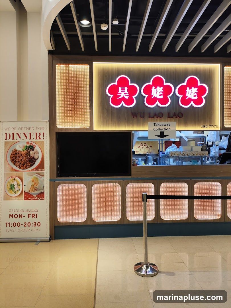A food stall with a prominent sign displaying "Wu Lao Lao" in Chinese characters and English. A banner on the left advertises dinner and lists opening hours. The counter area has a takeaway collection sign and appears to be a food service establishment.