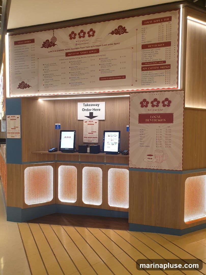 A takeaway counter for Wu Lao Lao, a restaurant. The counter has digital ordering screens and menus displayed on the wall. A sign indicates "Takeaway Order Here".