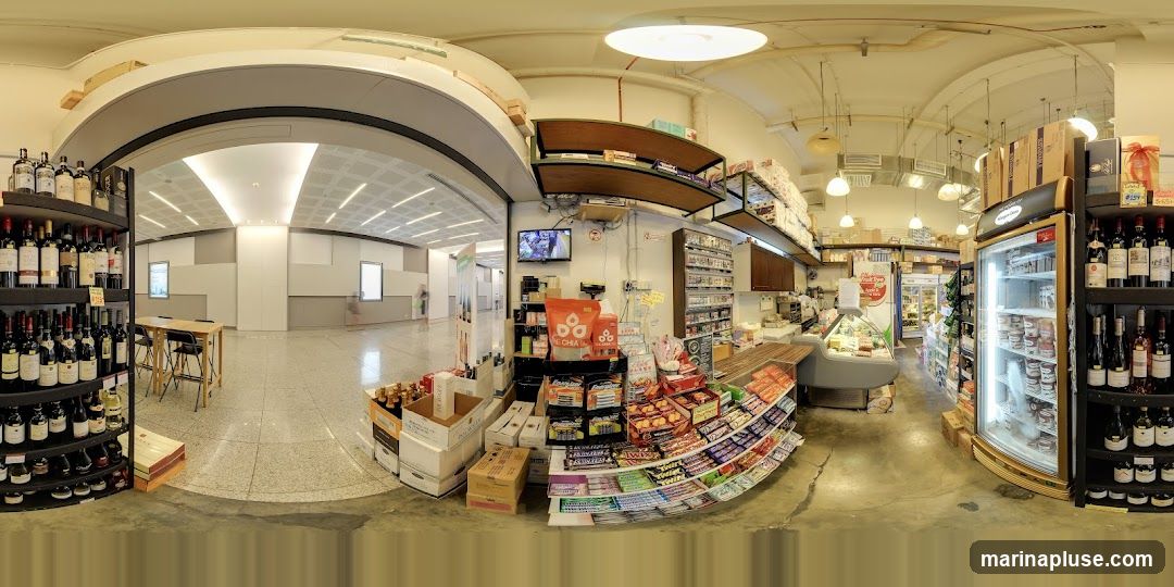 A panoramic view of the interior of a grocery store. Shelves are stocked with wine bottles, snacks, and other food items. Refrigerated display cases show various food products. A television screen is mounted on the wall. The store appears to be well-lit with overhead lighting.