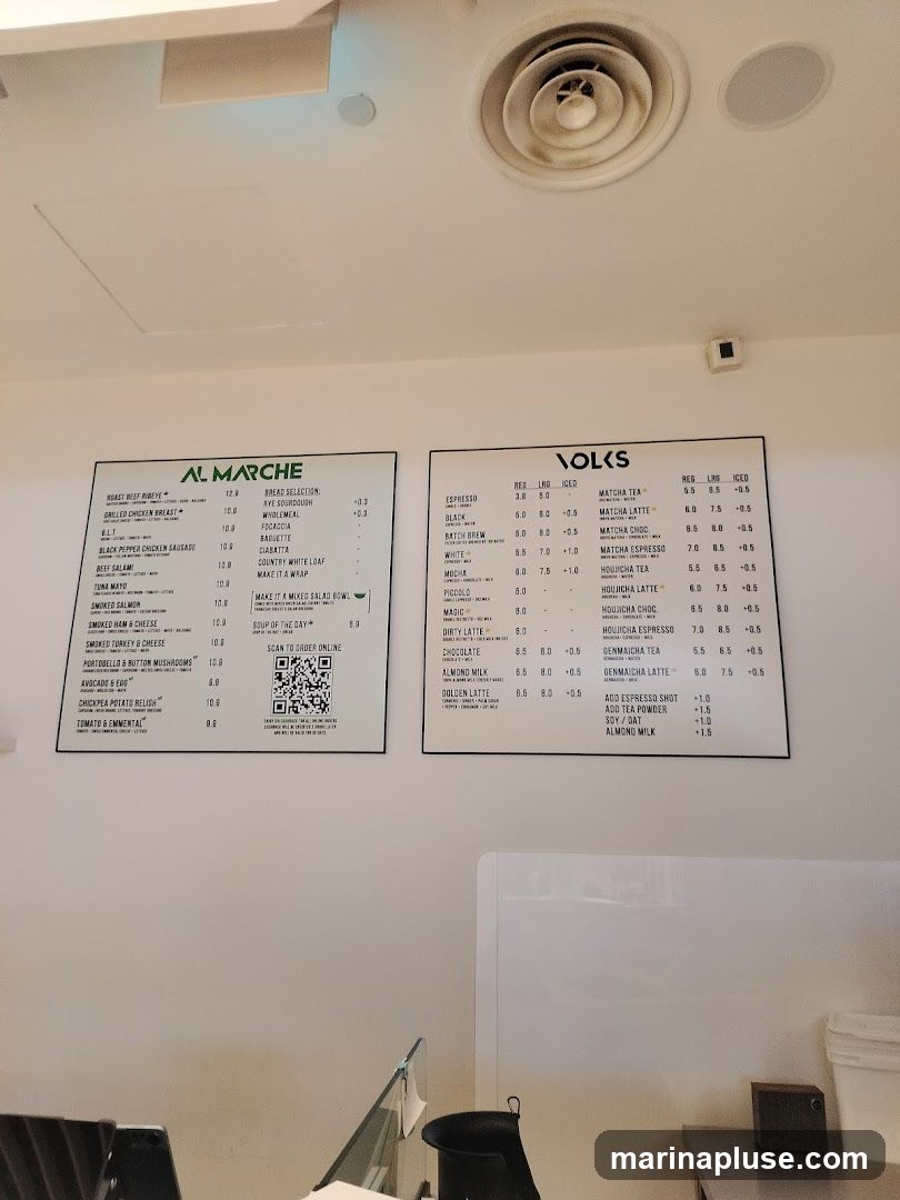 Two menus are displayed side-by-side. The left menu is for AL MARCHE, featuring sandwiches and soups. The right menu is for VOLKS, featuring various coffee and tea drinks.
