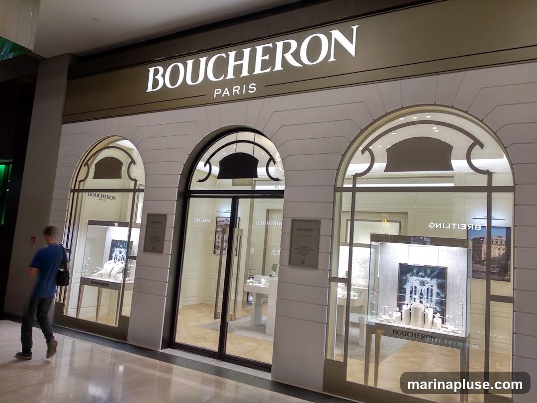 A Boucheron Paris jewelry store with a man walking past. The storefront features large arched windows displaying jewelry in illuminated cases. The Boucheron Paris logo is prominently displayed above the entrance.