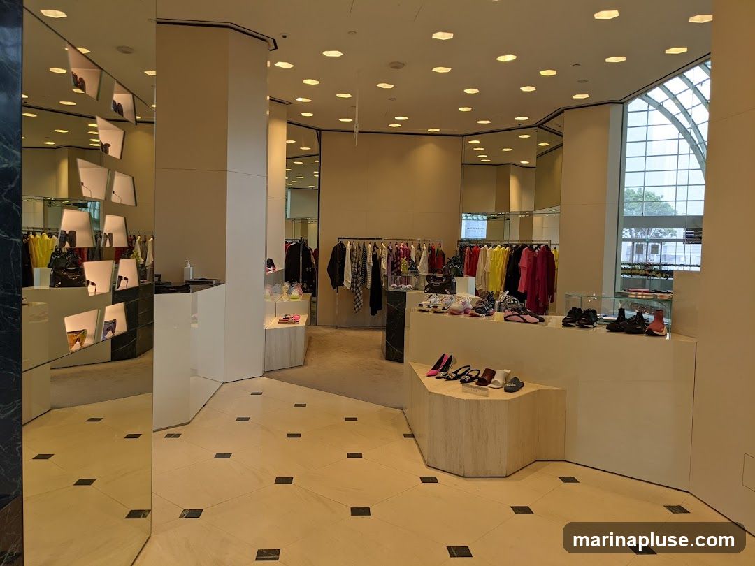 The interior of a well-lit retail store displays racks of colorful clothing and shelves of shoes. Mirrors are strategically placed throughout the space, reflecting the merchandise and creating an illusion of greater depth. The flooring is a light-colored tile with dark square accents. In the background, a large arched window offers a glimpse of the outside.