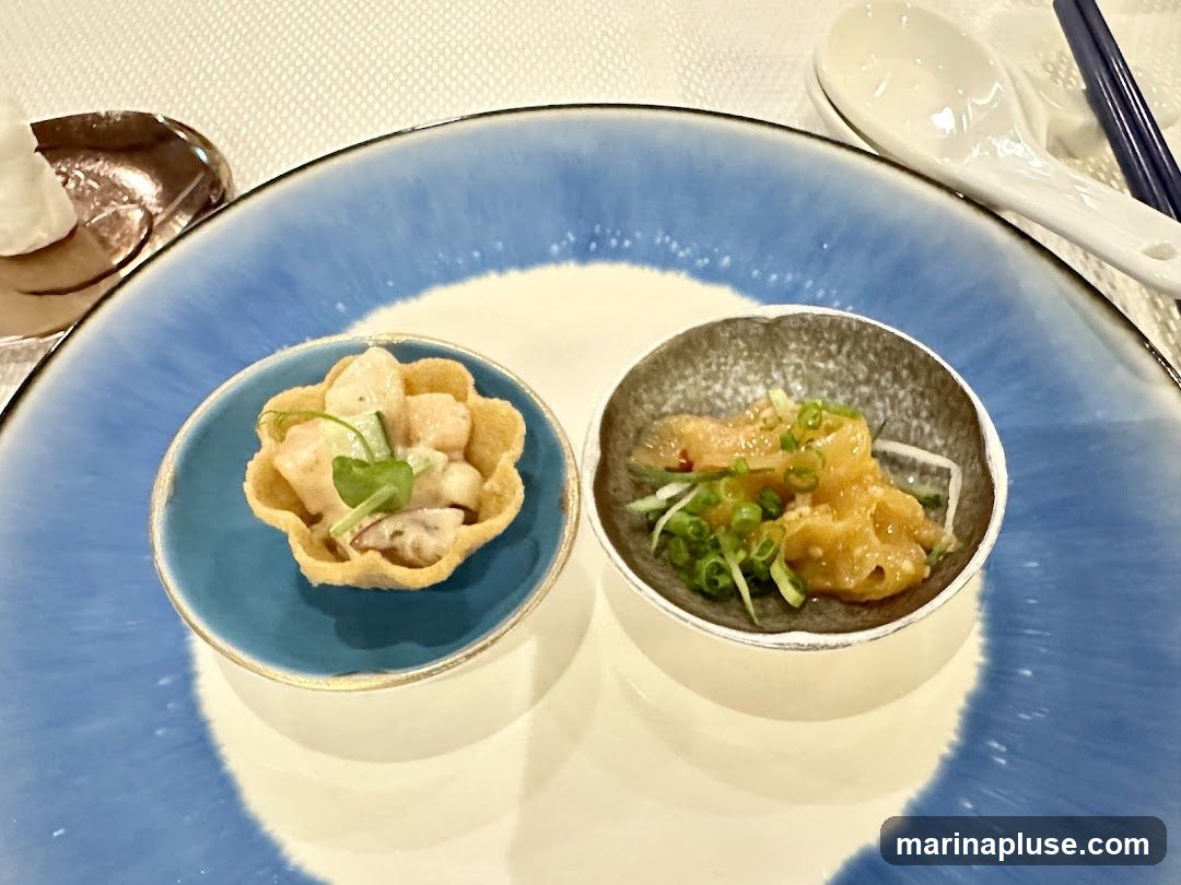 Two small appetizers are presented on a blue and white plate. The appetizer on the left is in a fluted pastry shell and appears to contain a creamy salad with small pieces of food and a microgreen garnish. The appetizer on the right is in a small bowl and consists of what looks like thinly sliced, marinated fish or seafood, mixed with chopped green onions and possibly some shredded cucumber. A spoon and chopsticks are visible in the background.