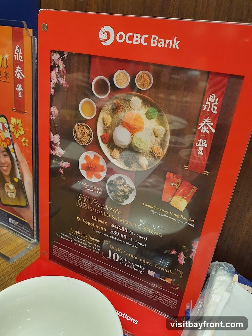 A promotional display for OCBC Bank featuring a Prosperity Smoked Salmon Yu Sheng dish. The display includes pricing for vegetarian and classic sets, as well as auspicious top-ups. It also highlights a complimentary Hong Bao set with a minimum spend and a 10% discount for OCBC Cardmembers.