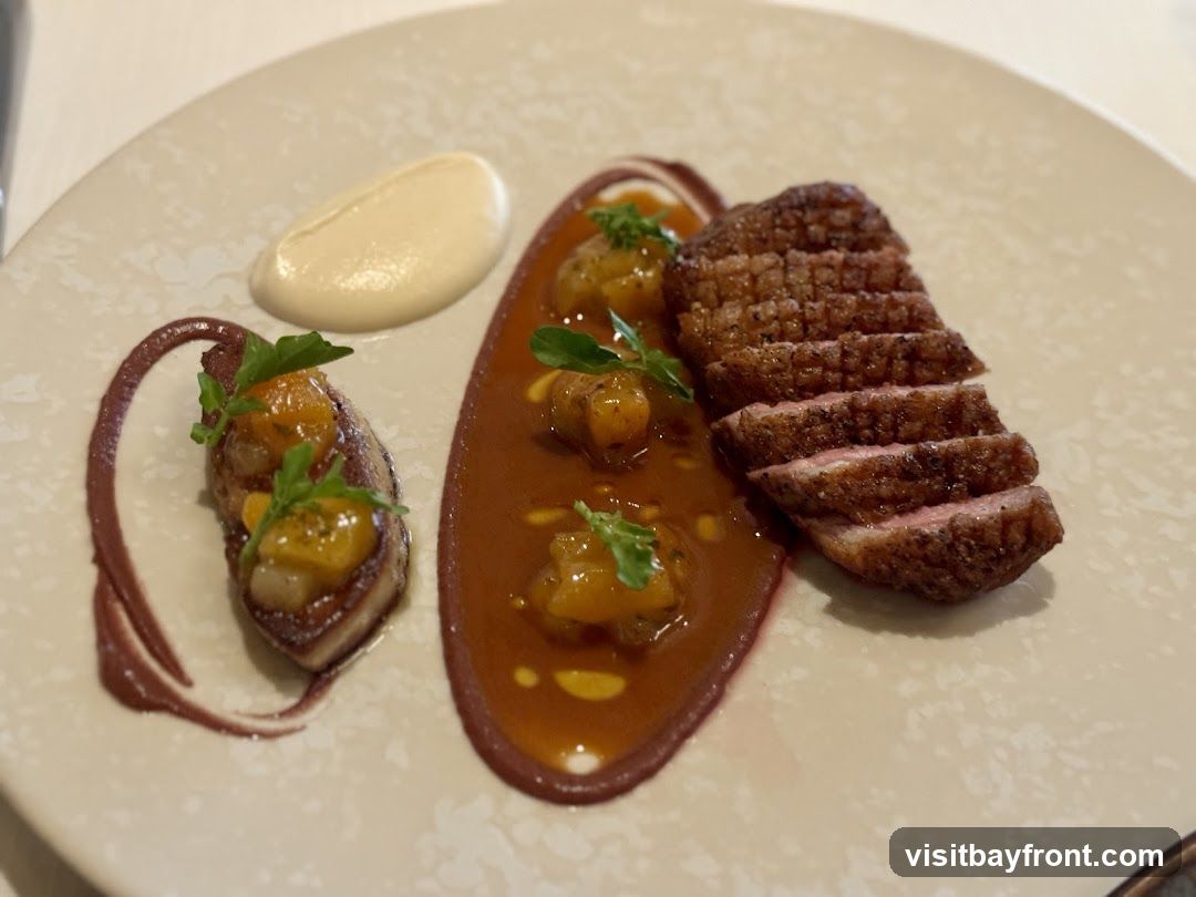 A plate of sliced duck breast with crispy skin, served with a dollop of white puree, a swirl of dark sauce, and a portion of duck or foie gras topped with diced fruit and garnished with herbs.