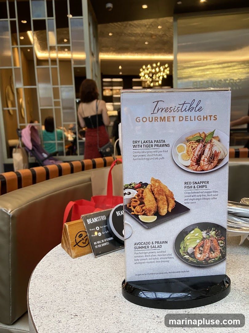 A menu displaying gourmet delights with images and descriptions of dishes. The menu includes Dry Laksa Pasta with Tiger Prawns, Red Snapper Fish & Chips, and Avocado & Prawn Summer Salad. There is also a sign indicating service and billing information.
