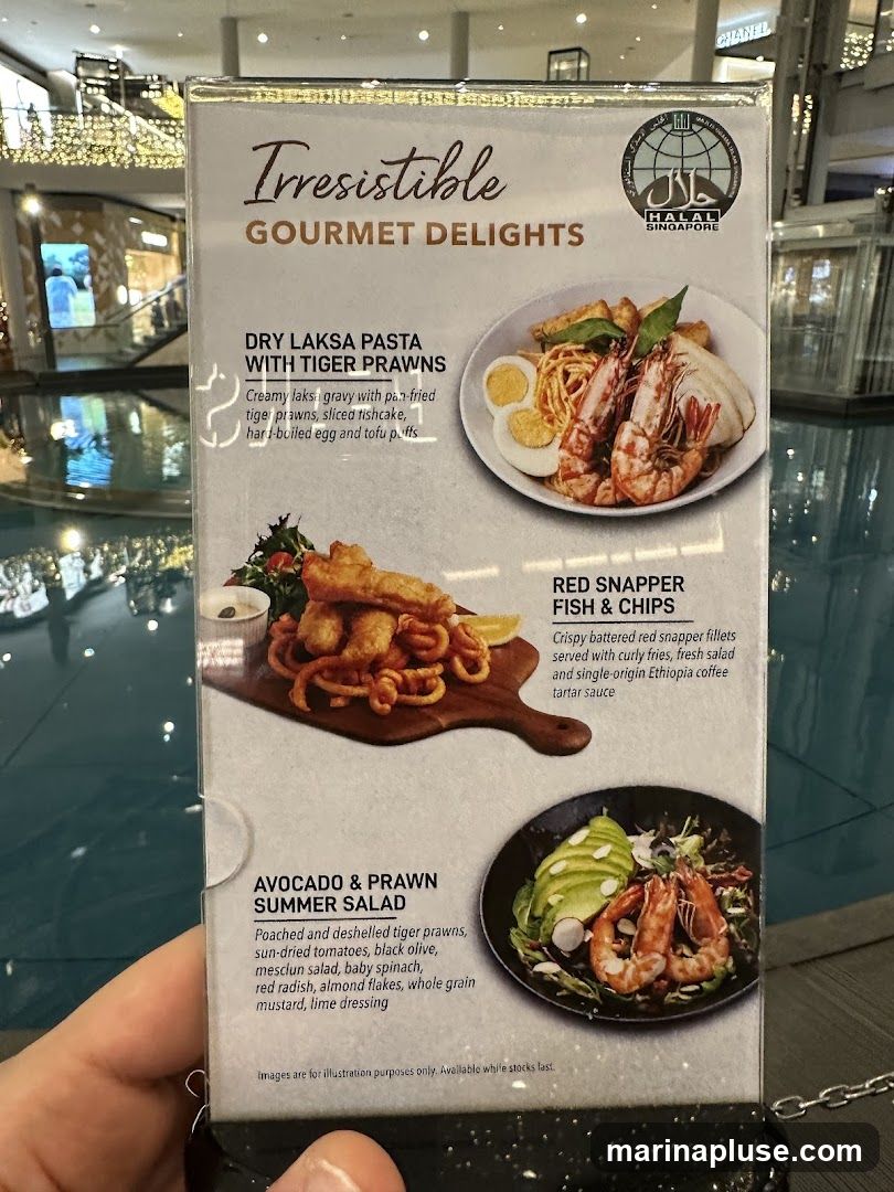 A menu featuring three dishes: Dry Laksa Pasta with Tiger Prawns, Red Snapper Fish & Chips, and Avocado & Prawn Summer Salad. The menu also indicates Halal certification for Singapore.