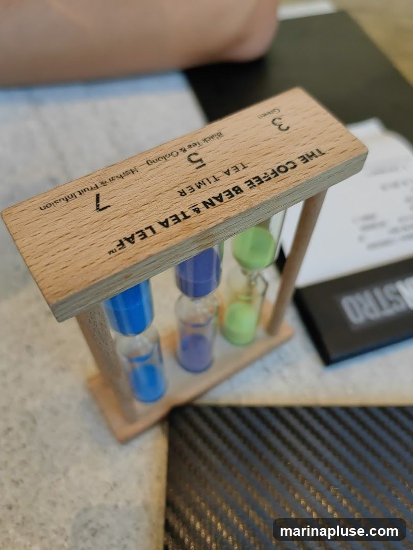 A wooden tea timer with three sand timers, labeled for different tea types and brewing times. The timer is branded with "THE COFFEE BEAN & TEA LEAF™".