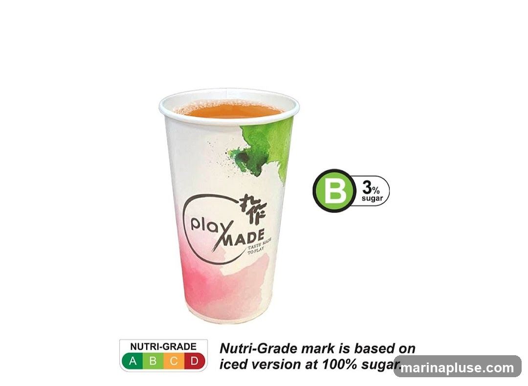 A paper cup with a watercolor design of pink and green splashes. The cup has the logo "play MADE" and the tagline "TASTE MADE TO PLAY". To the right of the cup is a green circle with the letter "B" inside, indicating a 3% sugar content. Below the cup is a Nutri-Grade label showing a spectrum from A to D, with the text "Nutri-Grade mark is based on iced version at 100% sugar."