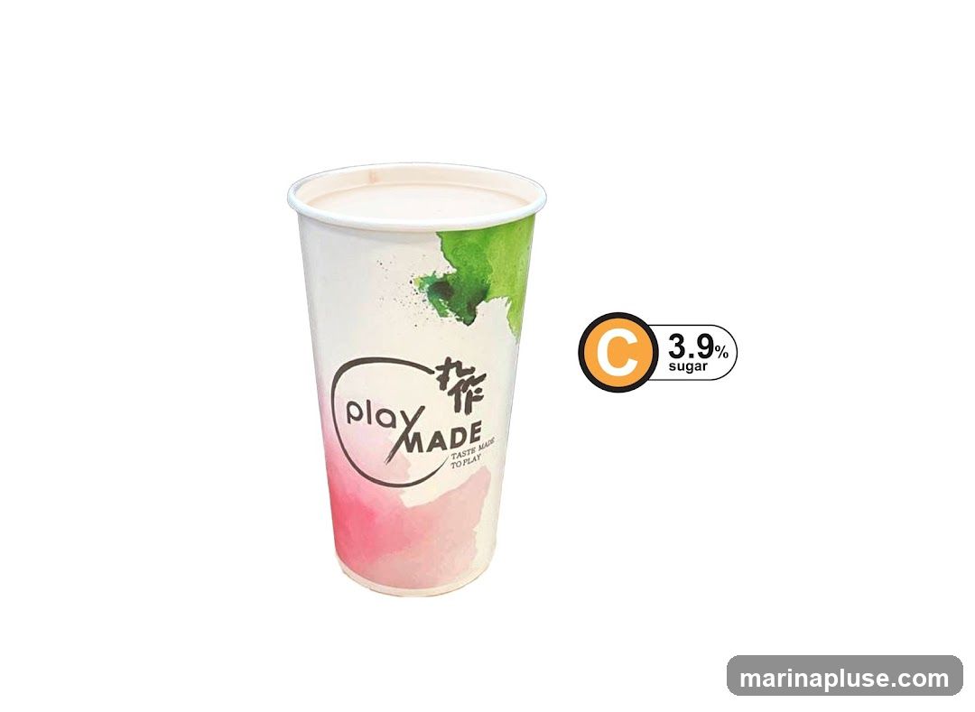 A white paper cup with a watercolor design of pink and green splashes. The cup has a black oval logo with the text "play MADE" and smaller text below that reads "TASTE MADE TO PLAY". To the right of the cup is a circular orange and black logo with a white 'C' inside, next to a label that says "3.9% sugar".