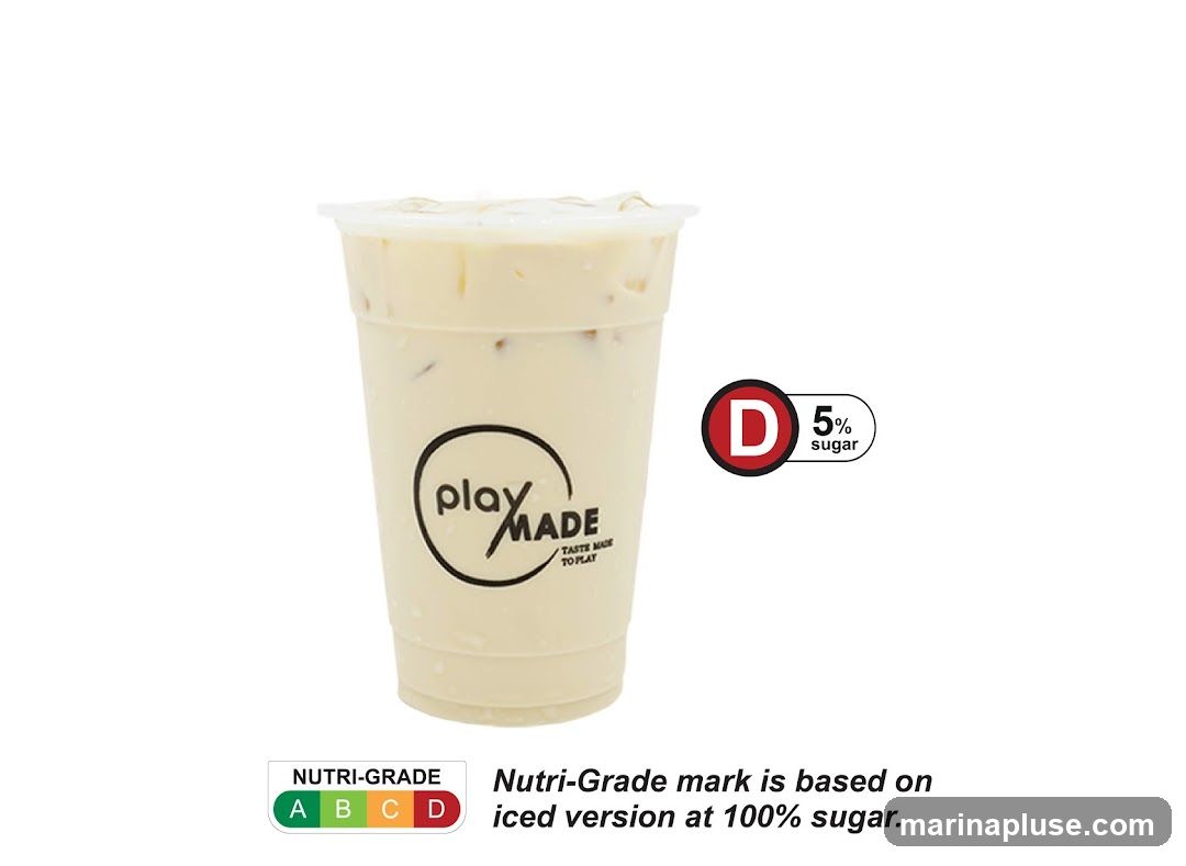 A plastic cup filled with a creamy, light-colored beverage with ice. The cup has a black and white logo that says "play MADE" with the tagline "TASTE MADE TO PLAY" below it. To the right of the cup is a red circle with a white "D" inside, next to text that reads "5% sugar". Below the cup, there is a "NUTRI-GRADE" label showing a spectrum from green "A" to red "D", with text explaining that the Nutri-Grade mark is based on the iced version at 100% sugar.