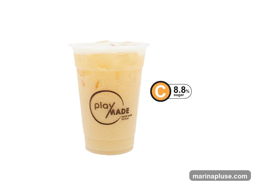 A plastic cup filled with a light yellow, frothy beverage, likely a drink. The cup has a circular logo that reads "play MADE" with the tagline "TASTE MADE TO PLAY" below it. To the right of the cup, there is a graphic indicating "C 8.8% sugar". The background is white.