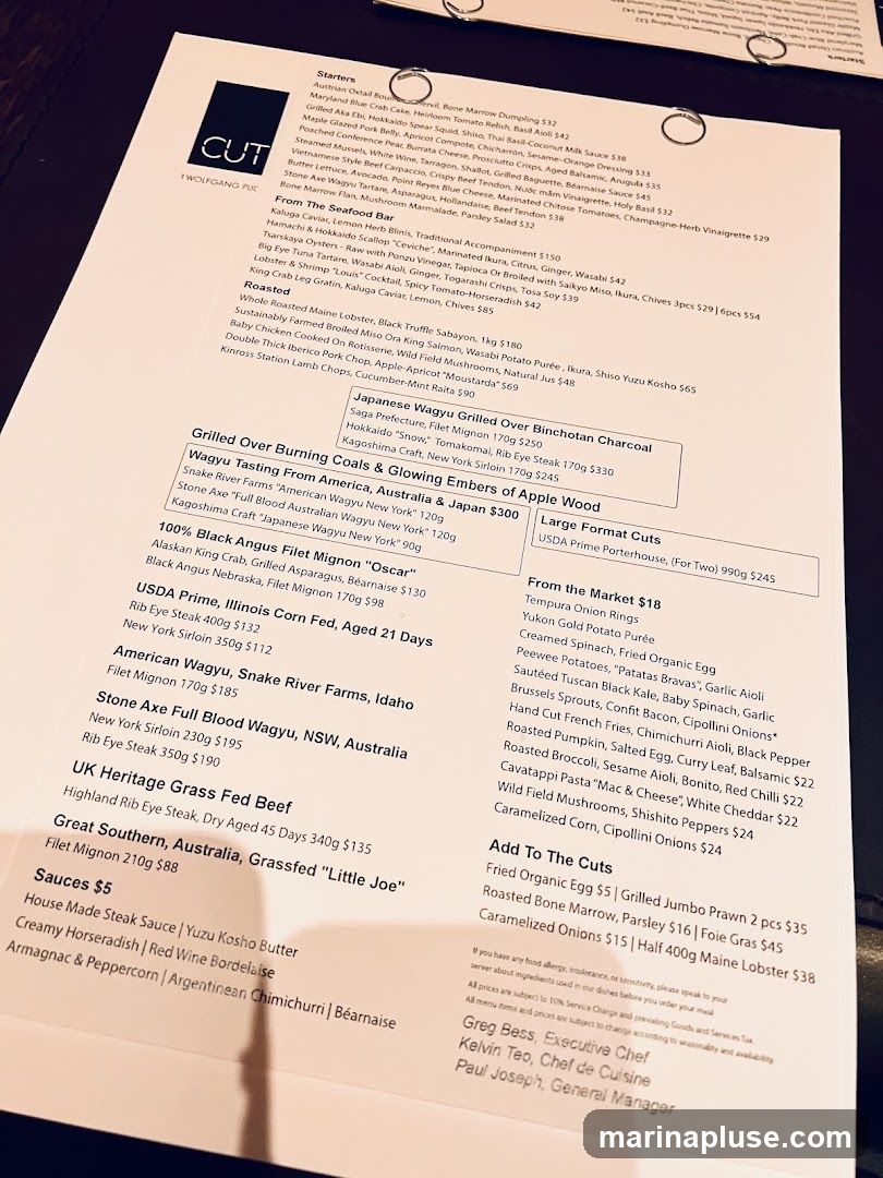 A menu from CUT by Wolfgang Puck, featuring starters, seafood, wagyu beef, other cuts of steak, and sauces.