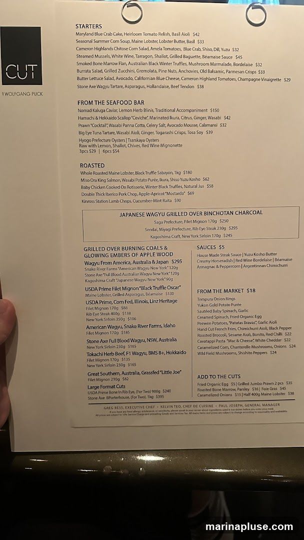 A menu from CUT by Wolfgang Puck, featuring starters, seafood, roasted dishes, wagyu selections, and sauces.