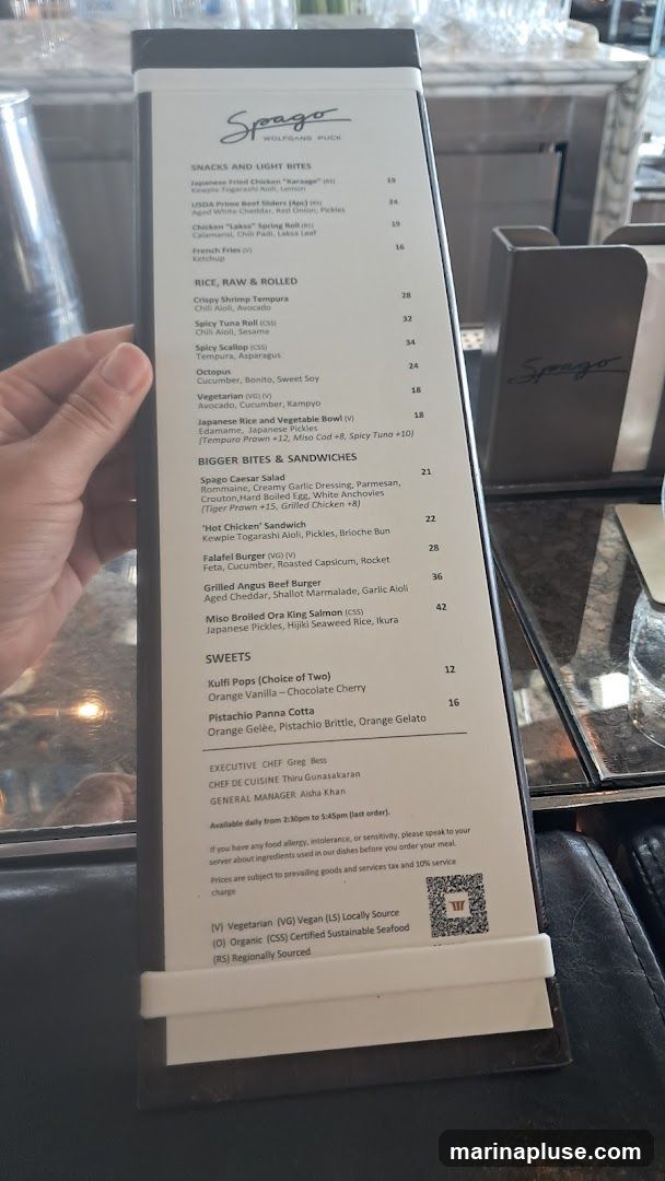A menu from Spago Wolfgang Puck featuring snacks, rice dishes, sandwiches, and sweets.