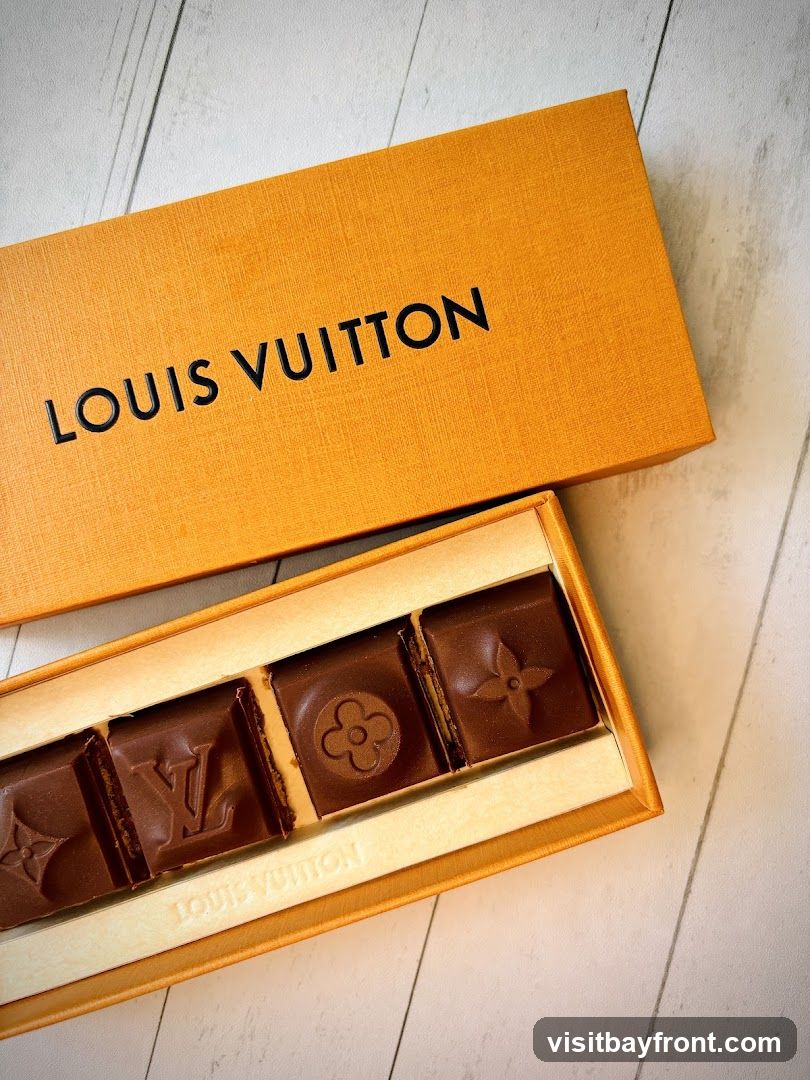 A box of Louis Vuitton chocolates with embossed logos and floral patterns on a light-colored, textured surface.