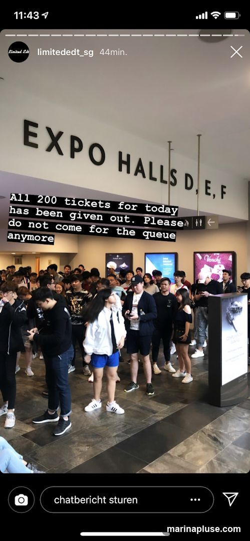 A crowd of people are gathered in front of a sign that reads "EXPO HALLS D, E, F". A message overlay states, "All 200 tickets for today has been given out. Please do not come for the queue anymore." There are several display boards and posters visible behind the crowd.