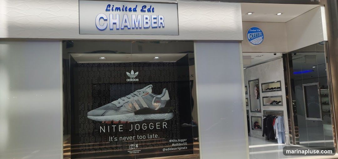 The exterior of a store with a large display window featuring an Adidas Nite Jogger shoe. The store has signage above the window that reads "Limited Edt CHAMBER". Inside the store, shelves display shoes and clothing.