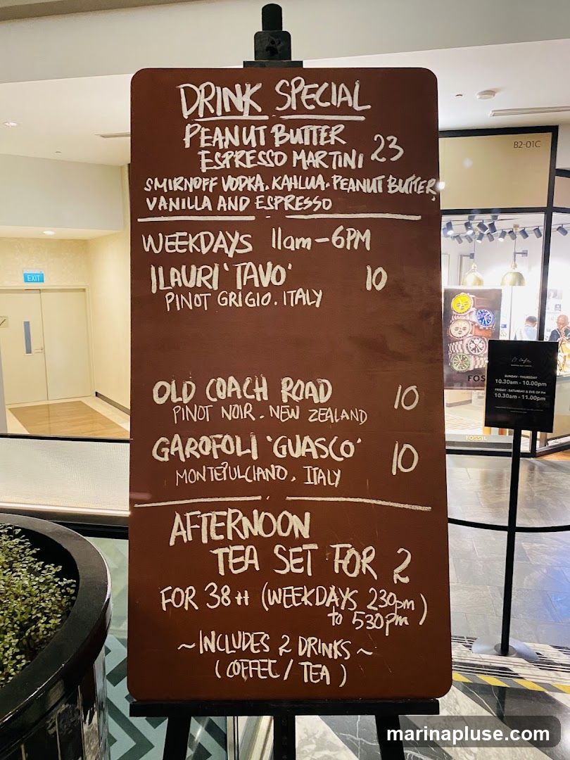A brown chalkboard menu displays drink specials and an afternoon tea set.
