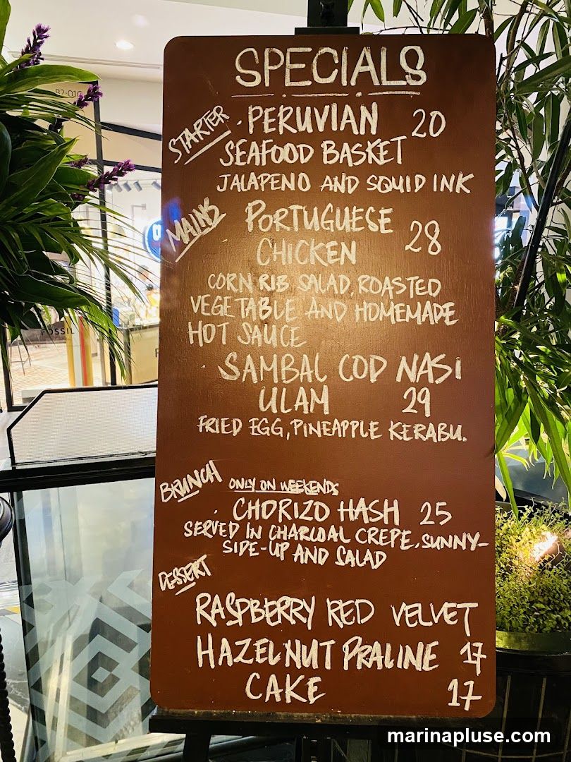 A brown wooden board with white chalk lettering listing specials.