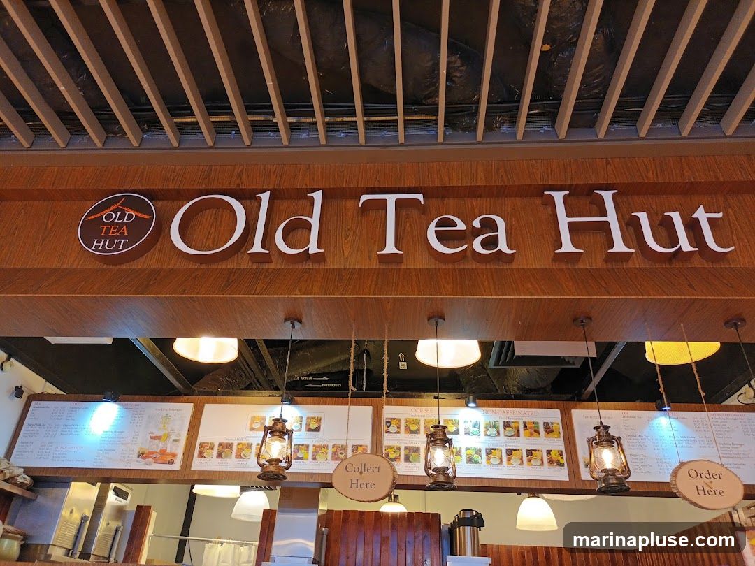 The image shows menu boards for Old Tea Hut. The signage "Old Tea Hut" is visible above the menu boards. The menu boards display various categories including Coffees, Non-Caffeinated, and Tea. There are also images of drinks and a sign that says "Collect Here" and "Order Here".