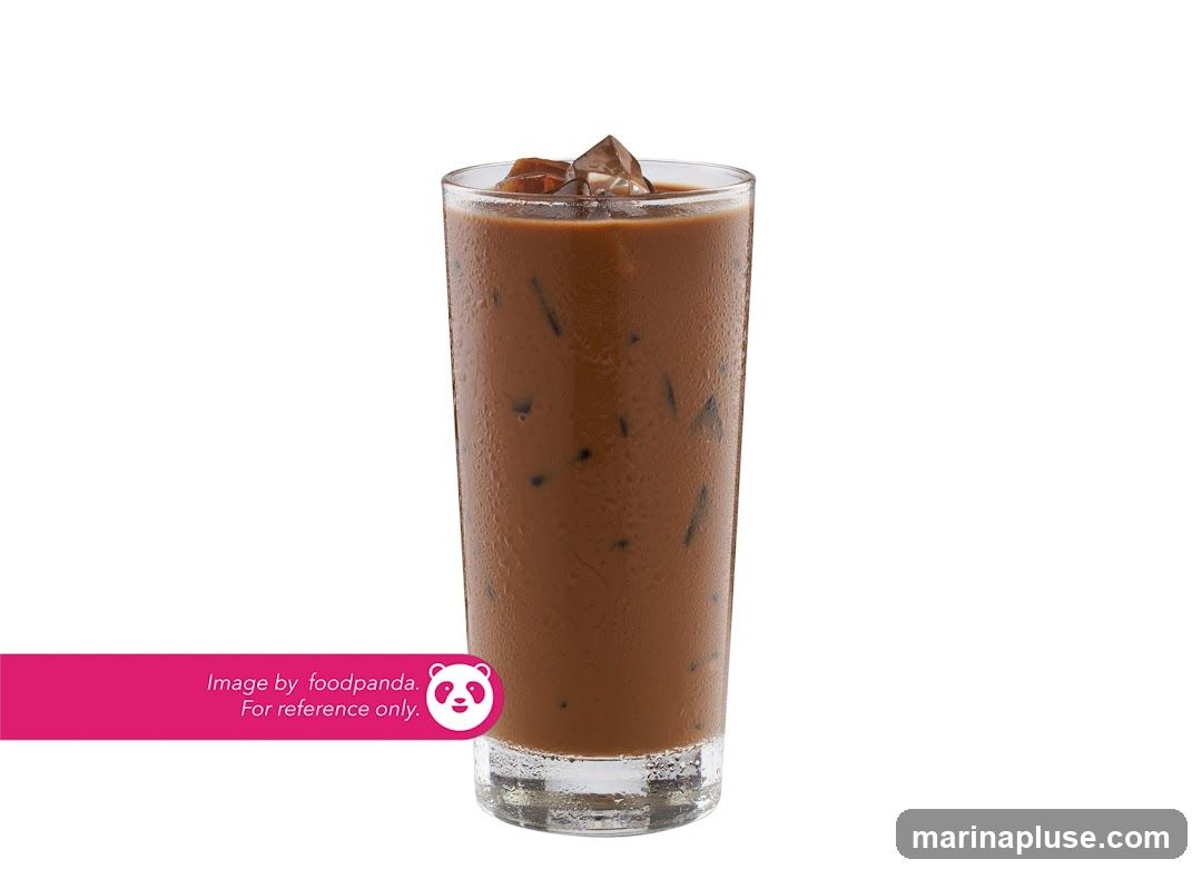 A tall glass of iced chocolate drink with ice cubes and condensation on the glass. A pink banner at the bottom left corner reads "Image by foodpanda. For reference only." with the foodpanda logo.