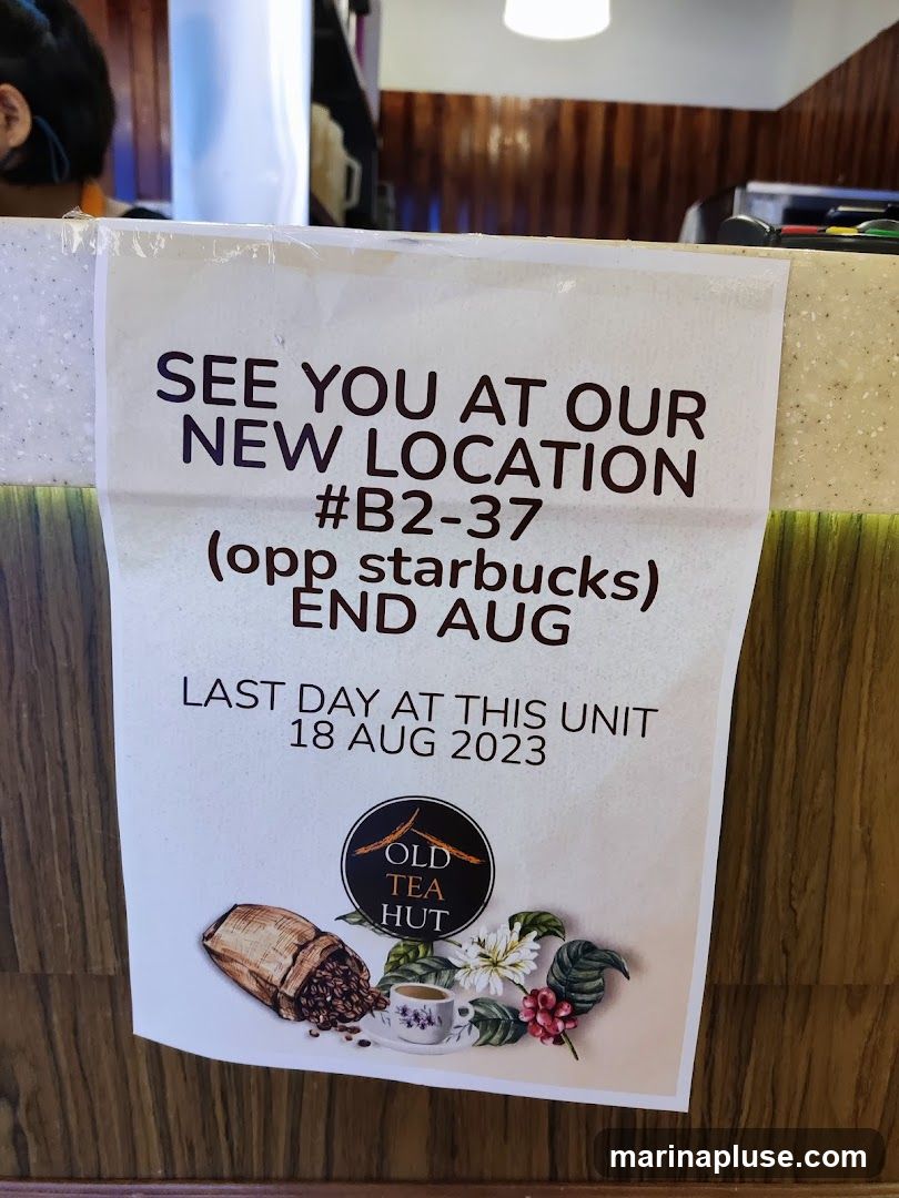 A sign announcing that Old Tea Hut is moving to a new location at #B2-37, opposite Starbucks, at the end of August. The last day at the current unit is August 18, 2023. The sign features the Old Tea Hut logo, an illustration of a coffee bag, a cup of coffee, and coffee plant elements.