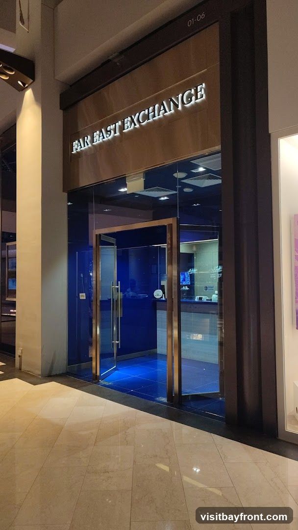 The exterior of a business with a glass entrance and a sign that reads "FAR EAST EXCHANGE". The interior is visible through the glass, showing a blue-tiled floor and a counter.