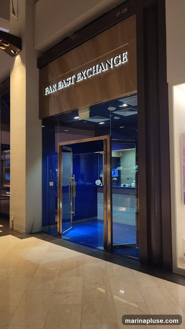 The exterior of a business with a glass entrance and a sign that reads "FAR EAST EXCHANGE". The interior is visible through the glass, showing a blue-tiled floor and a counter.