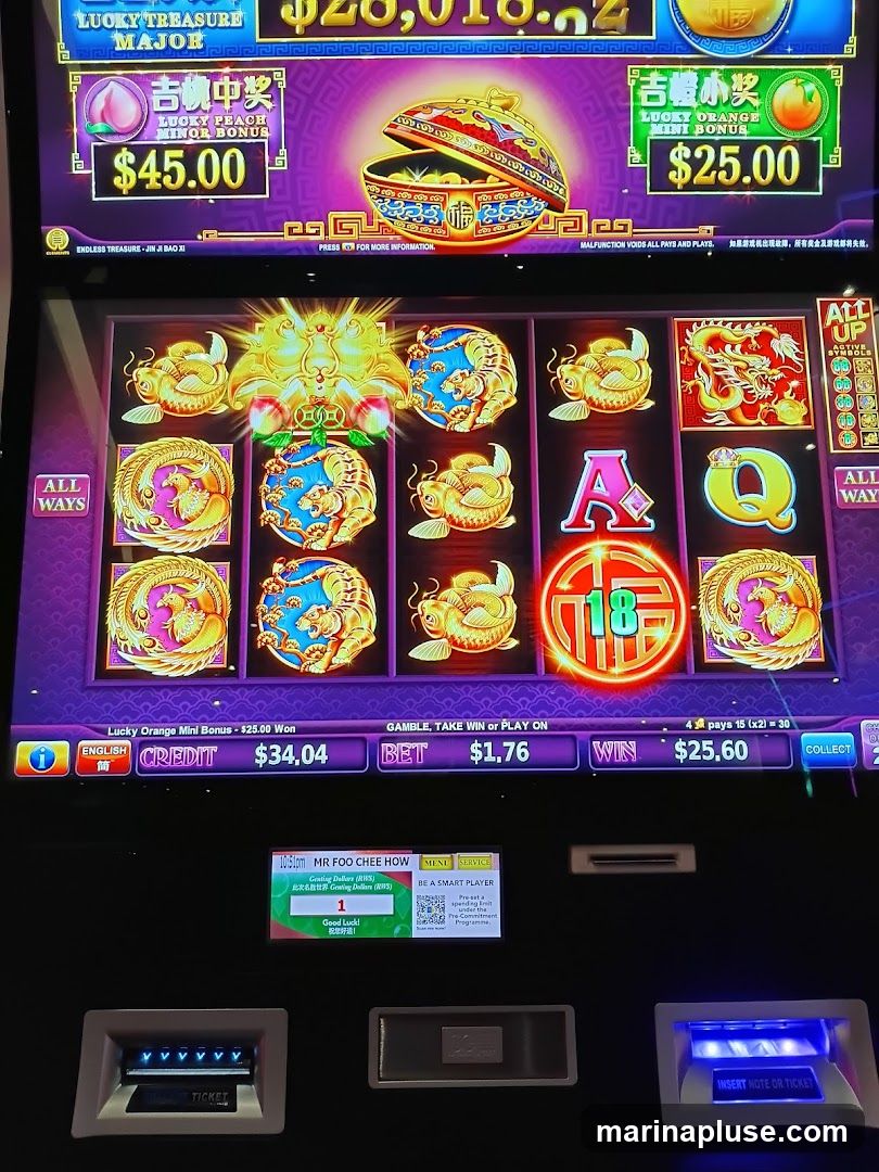 A close-up of a slot machine screen displaying a game with Chinese-themed graphics. The screen shows various bonus amounts, including "Lucky Peach Minor Bonus" for $45.00 and "Lucky Orange Mini Bonus" for $25.00. The game is in progress with symbols like dragons, tigers, and fish displayed on the reels. Below the reels, credit, bet, and win amounts are shown. A smaller screen displays a player's name, "MR FOO CHEE HOW," and a message "Good Luck!". The bottom of the machine has slots for inserting notes or tickets.