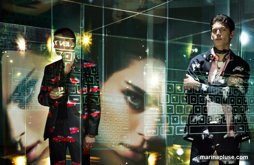 Two male models are shown wearing suits with a repeating pattern of red and white cars. The image is overlaid with a digital interface that includes a keyboard layout and text. The overall aesthetic is futuristic and high-fashion.