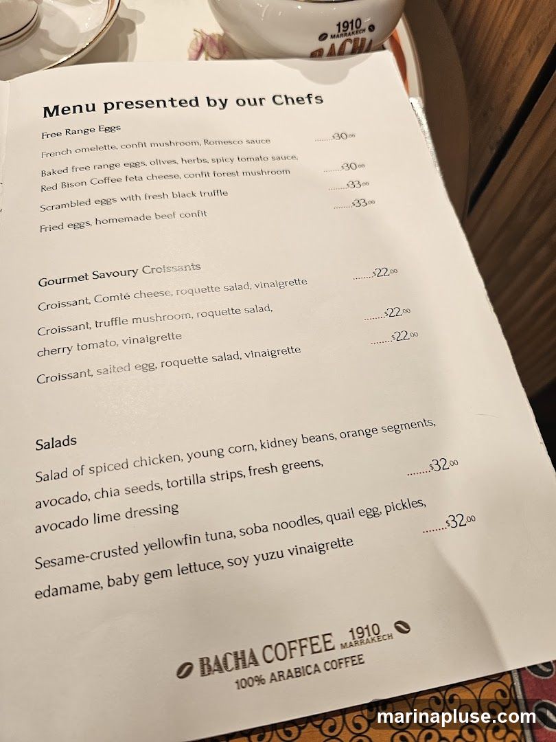 A menu from Bacha Coffee with sections for Free Range Eggs, Gourmet Savoury Croissants, and Salads.