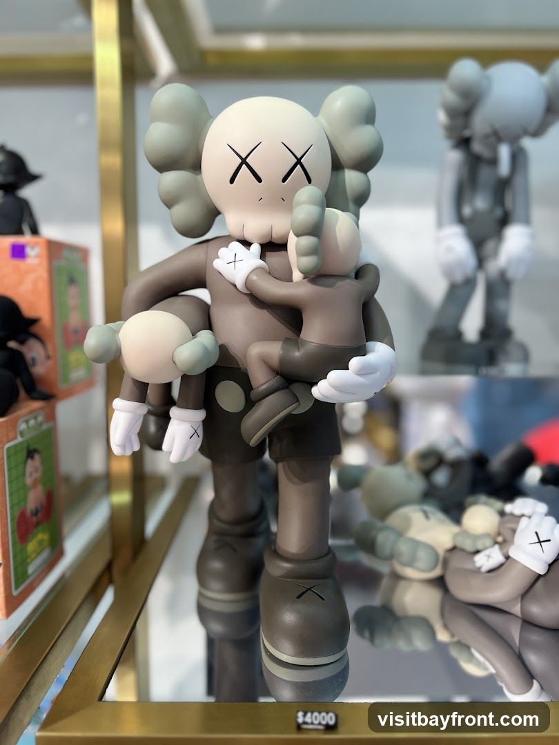 A display of KAWS Companion figures, with a large central figure holding smaller figures. The figures are brown and grey with the signature 'XX' eyes. In the background, other KAWS figures are visible, including a grey one in overalls and several lying down. A price tag of $4000 is visible at the bottom of the central figure.
