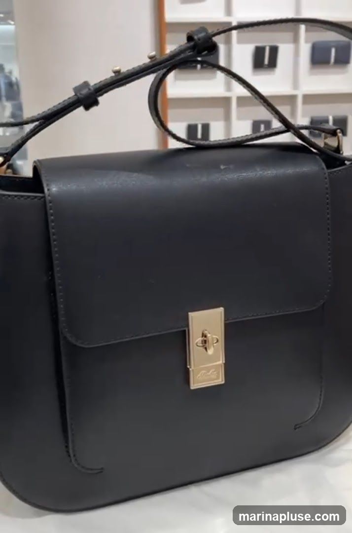 A close-up shot of a black leather handbag with a gold clasp. The background shows shelves with what appear to be more handbags or accessories.