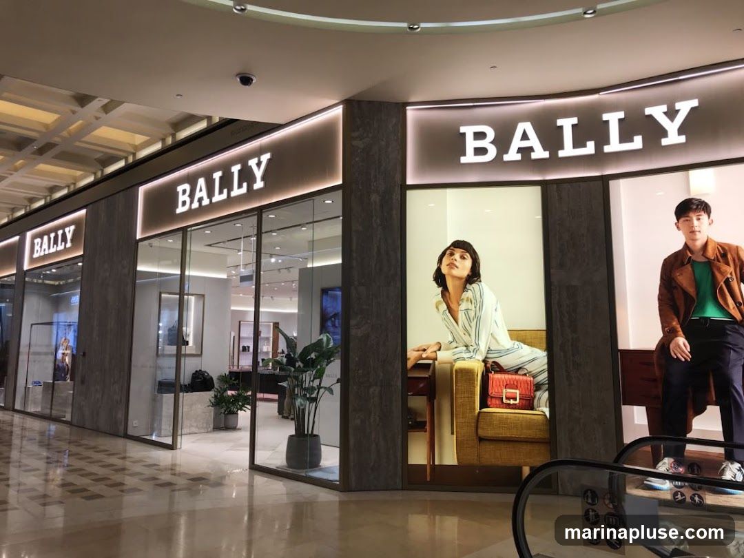 The exterior of a Bally store with large glass windows and prominent signage. Inside, displays of merchandise and mannequins are visible. Large advertisements featuring models are placed in the windows.