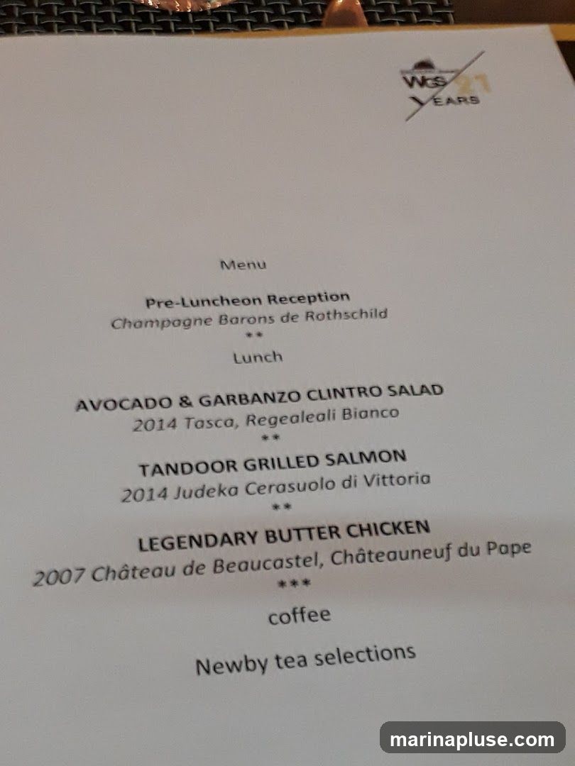 A menu with a logo indicating 21 years. It lists a pre-luncheon reception with Champagne Barons de Rothschild, followed by lunch options including Avocado & Garbanzo Clintro Salad, Tandoor Grilled Salmon, and Legendary Butter Chicken. The menu also includes coffee and Newby tea selections.