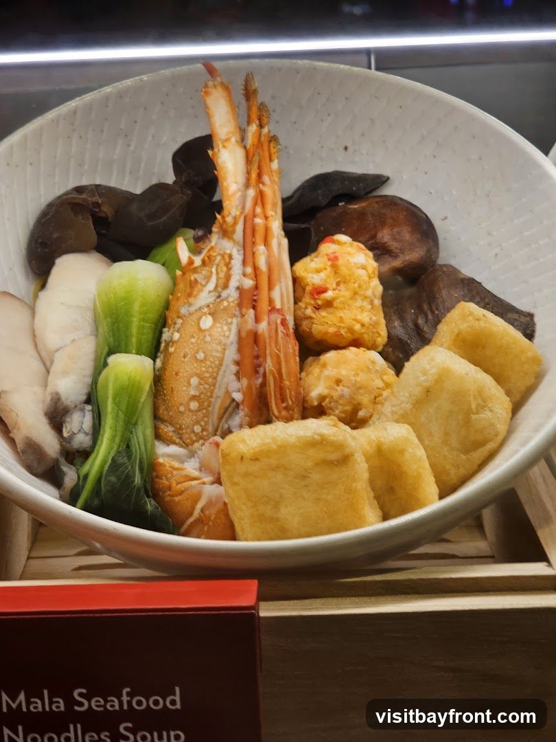 A bowl of Mala Seafood Noodles Soup with a lobster, fish slices, bok choy, mushrooms, fish balls, and fried tofu.