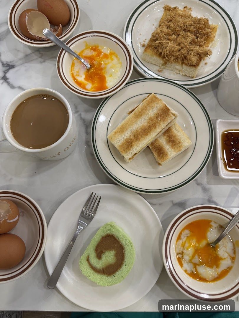 A top-down view of a breakfast spread featuring soft-boiled eggs, toast with shredded meat, kaya toast, a slice of pandan swiss roll, and a mug of coffee.