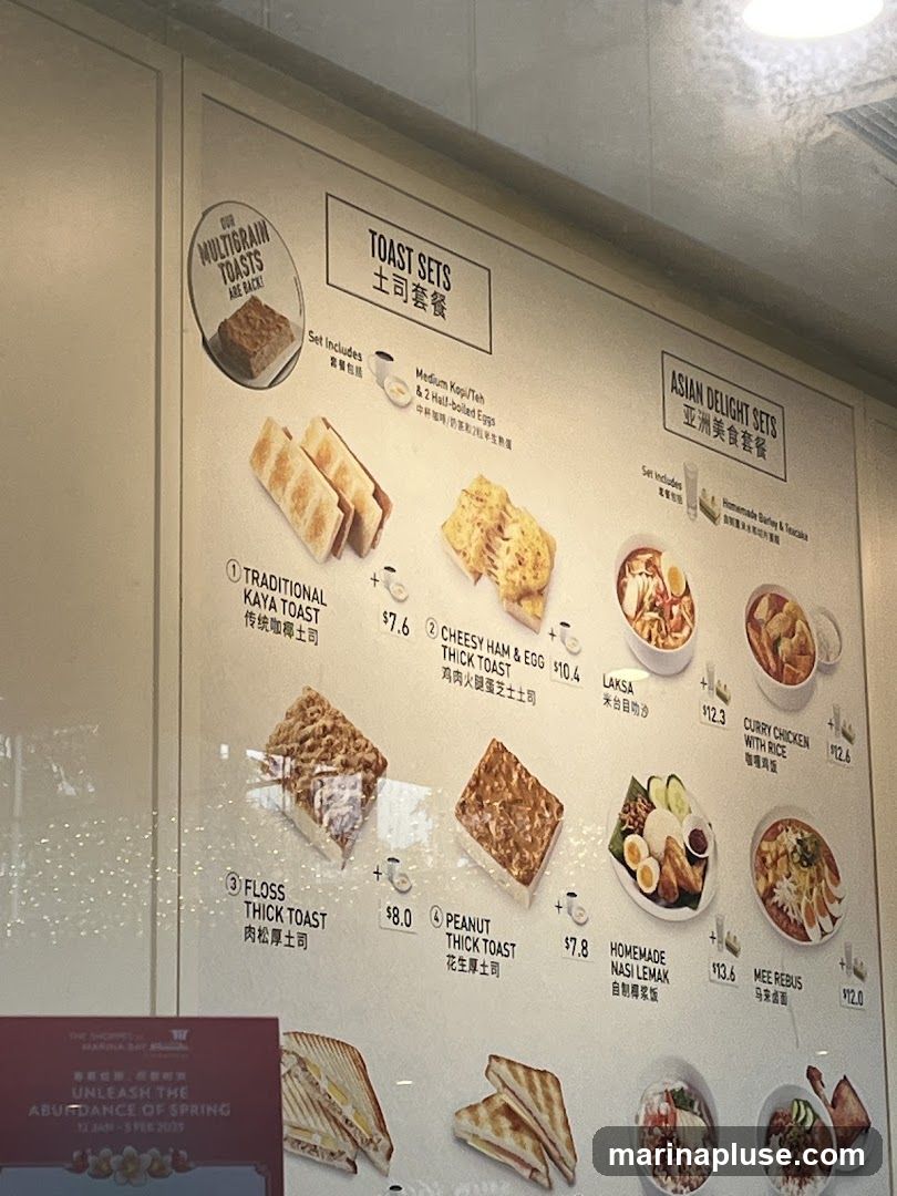 A menu board displaying various toast sets and Asian delight sets. The toast sets include Traditional Kaya Toast, Cheesy Ham & Egg Thick Toast, Floss Thick Toast, and Peanut Thick Toast. Each set includes a medium Kopi/Teh and 2 half-boiled eggs. The Asian Delight Sets include Laksa, Curry Chicken with Rice, Homemade Nasi Lemak, and Mee Rebus.