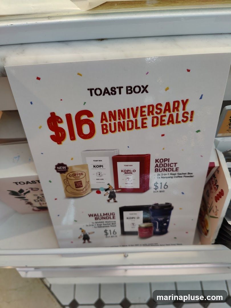 A promotional flyer for Toast Box's anniversary bundle deals. The flyer highlights two bundle offers: the "Kopi Addict Bundle" and the "Wallmug Bundle," both priced at $16. The Kopi Addict Bundle includes two boxes of 2-in-1 Kopi Sachets and one Nanyang Coffee Powder. The Wallmug Bundle includes a reusable wall mug and a jar of Hainanese Kaya.